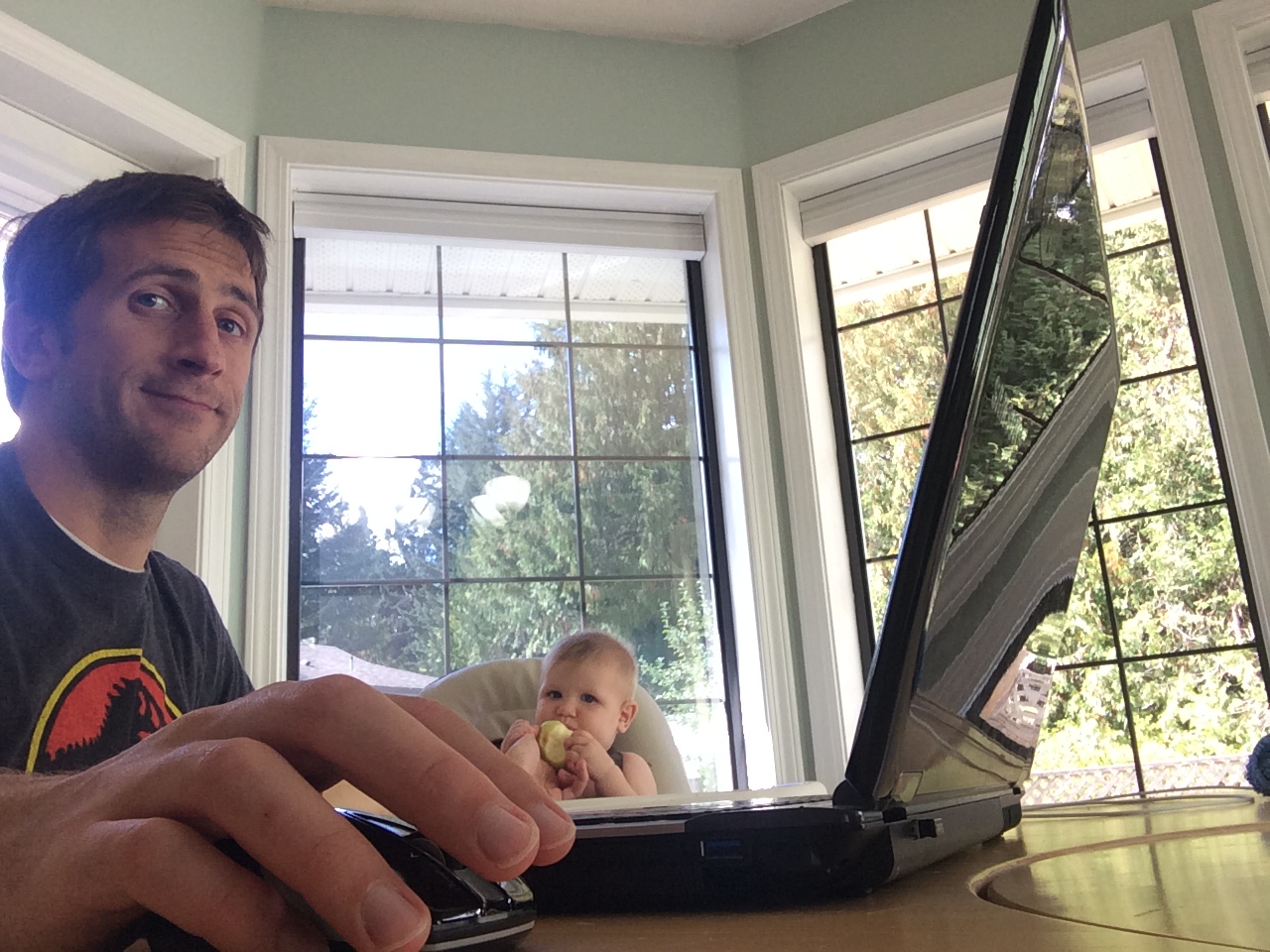 Mike Nelson working from home while feeding a baby
