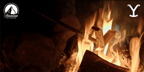 GIF of cowboy pulling a branding iron out of campfire